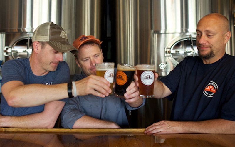 3 employees clinking beer glasses at Municipal Brew Works